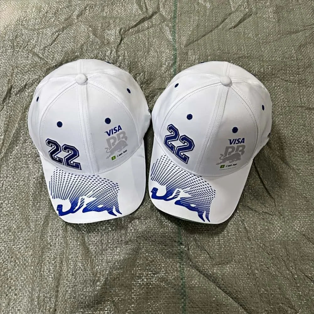 Two white baseball caps with blue and gray designs on a textured surface